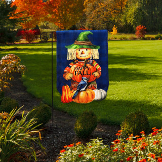 Happy Fall Scarecrow Burlap Garden Flag with green hat and pumpkins on blue background outdoors.