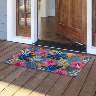 Pink and blue tropical floral coir doormat, 18 x 30 inches, on a wooden porch.