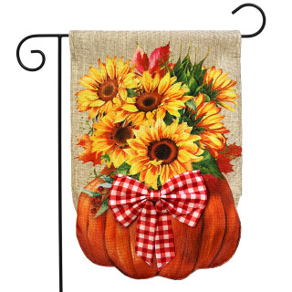 Sunflower filled pumpkin burlap garden flag with red plaid bow on black metal pole outdoors.