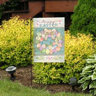 Pastel Easter Wreath Garden Flag with colorful eggs and bow on a garden stand outdoors.