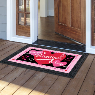 Black and pink Cupid's Hearts Doormat with Valentine's Day message on wooden porch outside doorway.