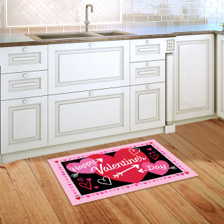 Pink border Valentine's Day doormat with hearts and text on a wooden kitchen floor beside sink.