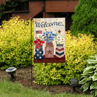 American mason jars garden flag with welcome message and floral design on a garden stand outdoors.
