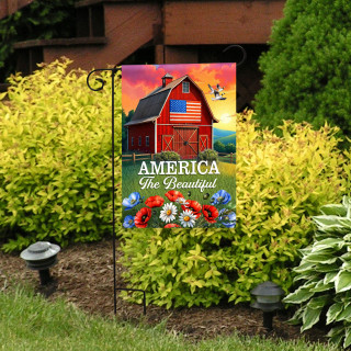 American Barn Garden Flag with red barn, American flag, and colorful flowers on a garden stand.