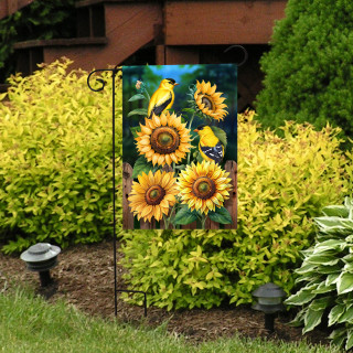 Goldfinch Gathering Garden Flag with sunflowers and goldfinches on display in a garden setting outdoors.