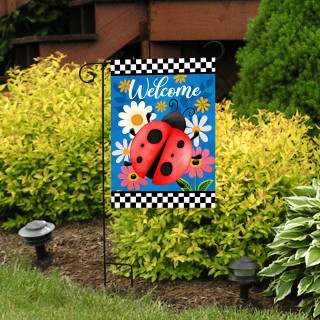 Ladybug Welcome Garden Flag with colorful flowers and "Welcome" text on a blue background displayed outdoors.