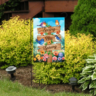 Spring Has Sprung Sign Garden Flag with colorful flowers and birds on a garden stand outdoors.