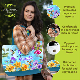 Woman holding large blue canvas tote with colorful floral design and All Things Are Possible text.