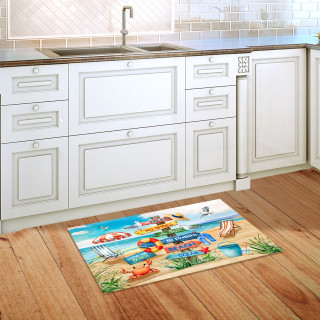 Beach themed doormat on wooden floor in front of white kitchen sink and cabinets.