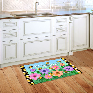 Busy Bees Doormat with colorful flowers and bees on a kitchen floor beside white cabinets.