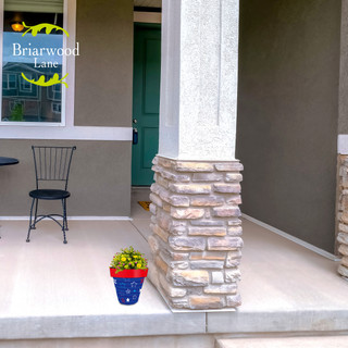 Small blue Star Spangled Planter with red rim and green plant on a house porch.