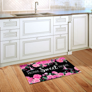 Black doormat with pink flowers and hummingbirds, "Home Sweet Home" in white on wooden floor.