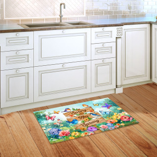 Spring Has Sprung Sign Doormat with colorful floral design and bunny on wooden floor by kitchen sink.