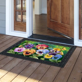 Pansy Trio Doormat with colorful pansy flowers on a black background and decorative border outside doorway.