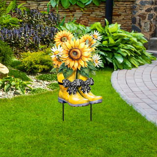 Yellow rain boots with sunflowers and daisies on a metal stand in a garden setting outdoor decor.