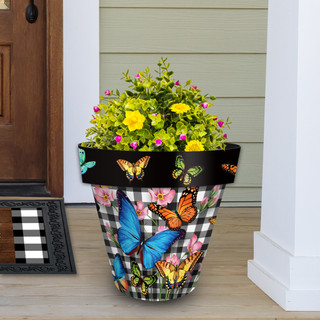 Large Checkered Butterflies planter with colorful butterflies and flowers on a porch with green siding.