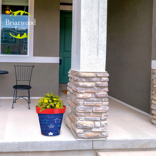 Star Spangled Medium Planter, blue ceramic pot with white stars and yellow flowers on a porch.