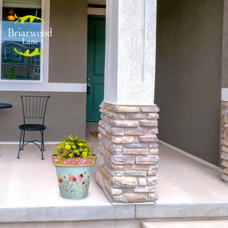 Wildflowers Medium Planter with yellow flowers on a porch with a stone base and floral design.