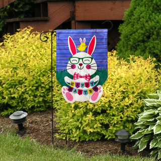 Happy Easter Bunny burlap garden flag with colorful bunny and crown on blue background outdoors.