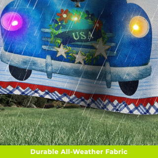 Blue pickup truck garden flag with USA wreath LED lights on burlap material outdoors in rain.