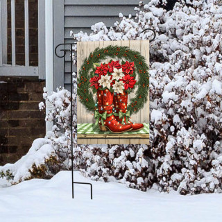Christmas Cowboy Boots Garden Flag with red boots and wreath on a snowy outdoor display stand.