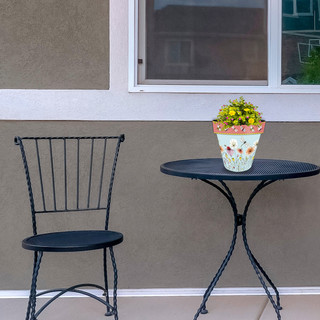 Small black metal table and chair with Wildflowers Small Planter on top with yellow flowers.