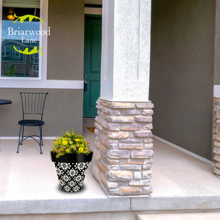 Geometric Floral Medium Planter with yellow flowers on a porch next to a stone pillar outdoors.