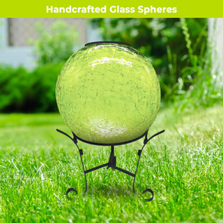 Green Cracked Solar LED Glass Gazing Ball on black metal stand outdoors on grassy lawn.