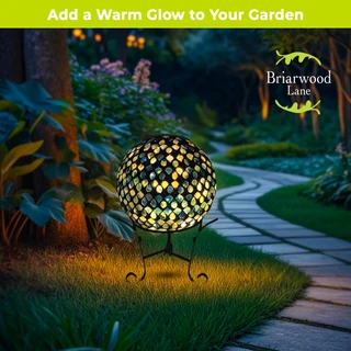 Organic purple and green solar LED glass gazing ball on stand in garden with warm yellow glow.