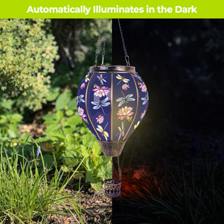 Dragonflies Solar Balloon lantern, blue with floral design, glowing in the dark outdoors.