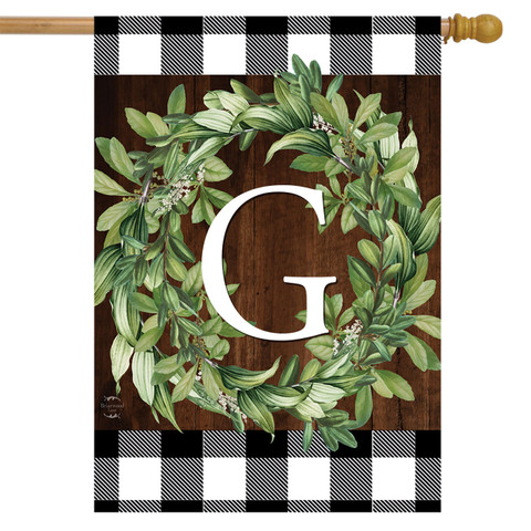 Briarwood Lane monogrammed house flag with greenery wreath and checkered border on a wooden background.