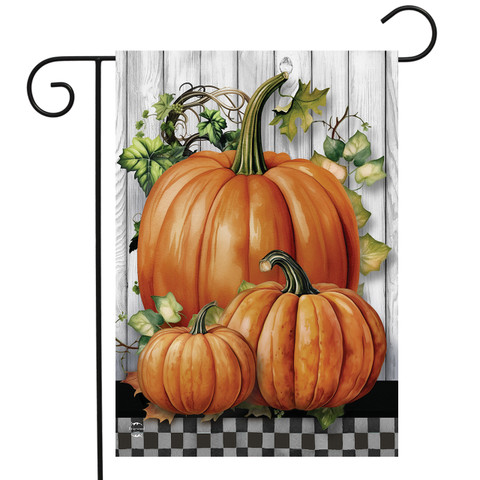 Country Pumpkins Garden Flag with three orange pumpkins and green leaves on a wood background.