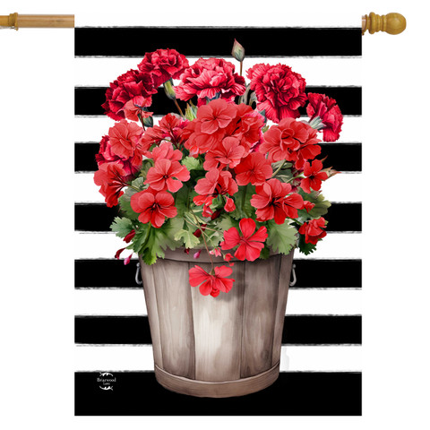 Striped house flag with red geraniums in a wooden bucket on black and white stripes background.