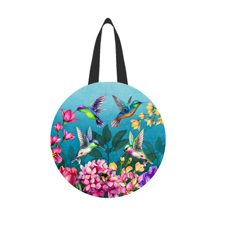 Vibrant round tote bag with colorful hummingbirds, flowers, and green leaves on blue background, black straps.