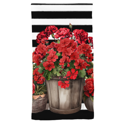 Red geraniums in wooden bucket on striped cotton hand towel with black and white stripes.