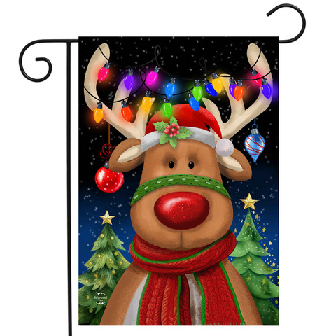 Festive Reindeer Garden Flag with red scarf and hat, colorful lights, and Christmas trees background.