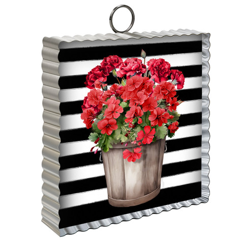 Red geraniums in a wooden bucket on black and white striped background, mini metal moment ornament.