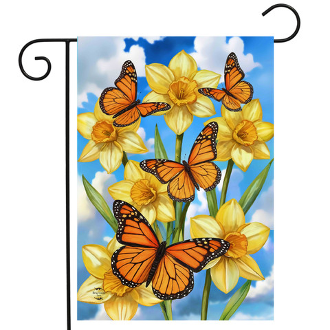 Monarch Butterflies Garden Flag with yellow daffodils and orange butterflies on blue cloudy sky background.