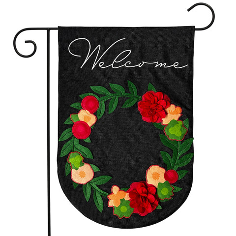 Black garden flag with floral wreath and welcome text, burlap material, red and peach flowers.