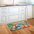 Briarwood Lane 5 O'Clock Paradise Summer doormat with colorful parrot and tropical design on wooden floor.