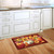 Briarwood Lane Fall Beauty Floral doormat with sunflowers, pumpkins, and welcome text on kitchen floor.
