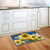 Briarwood Lane Sunflowers and Bees Summer Doormat on a wooden kitchen floor beside white cabinets.