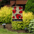 Briarwood Lane Ladybug Gathering Burlap Garden Flag with red ladybugs and welcome text on stand outdoors.