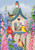 Briarwood Lane spring yard flag with bluebirds, cardinals, flowers, and birdhouse on a fence.