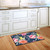 Briarwood Lane Watercolor Floral Spring Doormat on wooden kitchen floor with white cabinets background.