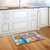Briarwood Lane Spring Floral colorful doormat on wooden floor in front of white kitchen sink area.