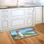 Briarwood Lane Coastal Lighthouse Nautical Doormat on wooden floor in front of white kitchen cabinets.