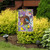 Briarwood Lane Teapot Birdhouse Spring Garden Flag with colorful birds and flowers on a garden display.