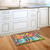 Briarwood Lane Gerber Daisy Watering Can doormat on wooden floor in front of white kitchen sink.