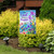 Briarwood Lane With God garden flag with colorful floral design and birds on a garden stand.